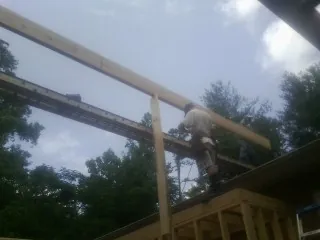 Carpenter setting a ridge beam over a new addition frame — Ice Dam Removal by Roofing Brothers in Wolcott