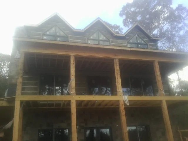 Dormers and porch framing on a large log home under construction — Roof Coating work by our crew in Wolcott